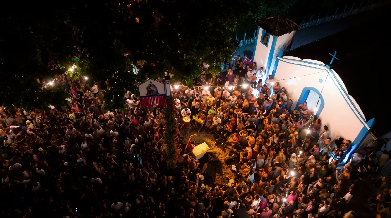 Multidão reunida à noite diante da igreja de Caraíva durante a festa da vila