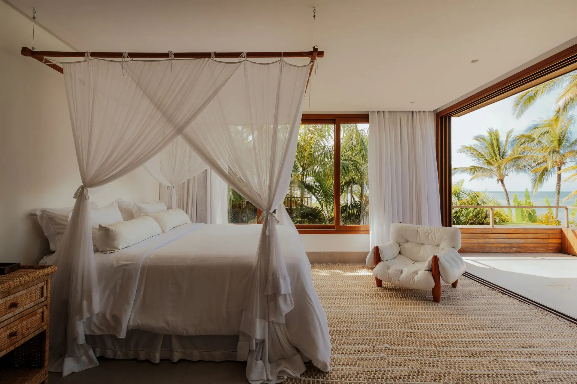 Suite with a white canopy bed and a view of the palm trees, at Falésia