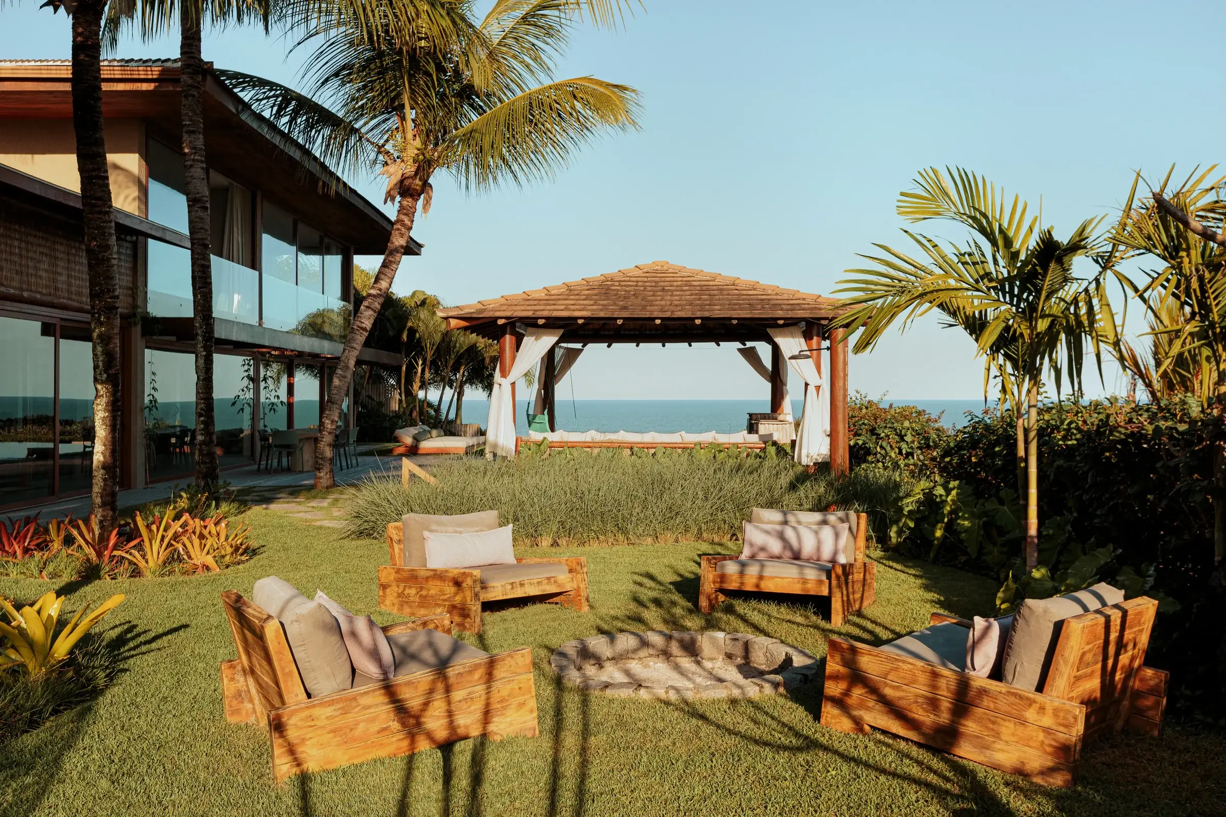Thatched gazebo and lounge on the Arraial Blue lawn, among palm trees