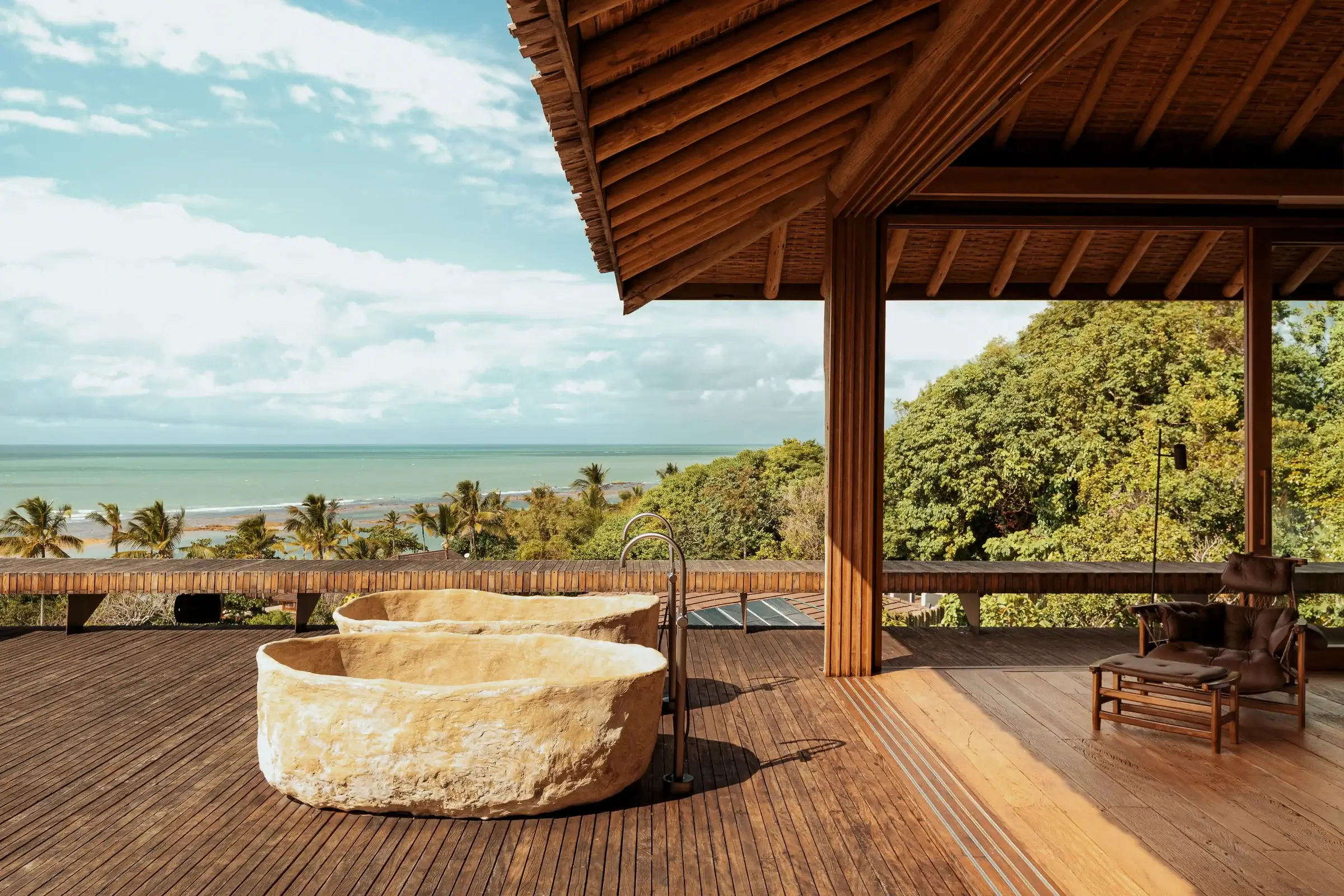 Deck with a stone fire pit under a wooden roof, sea behind