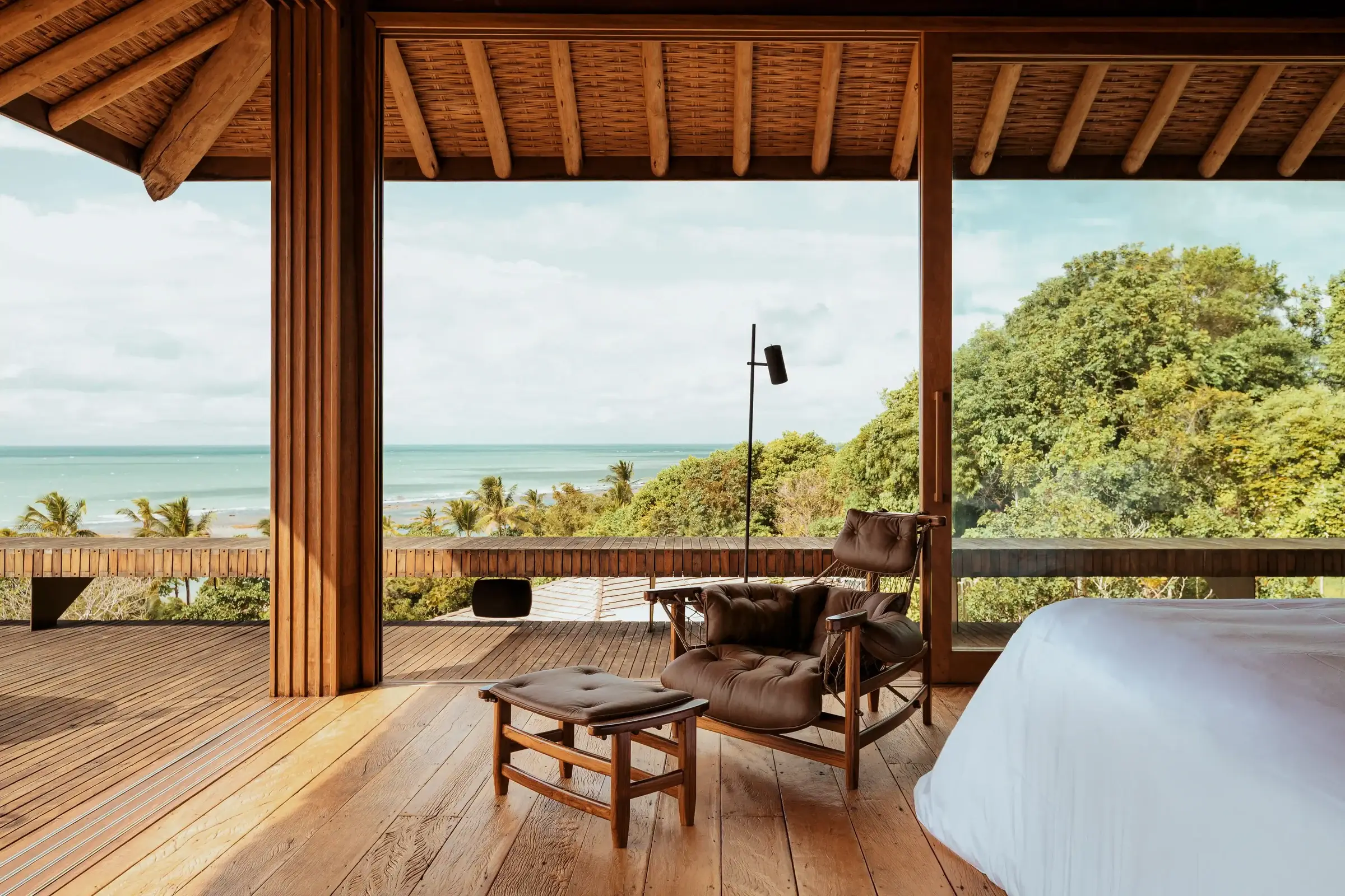 Suite with a bed and leather armchair, open to the deck and the sea