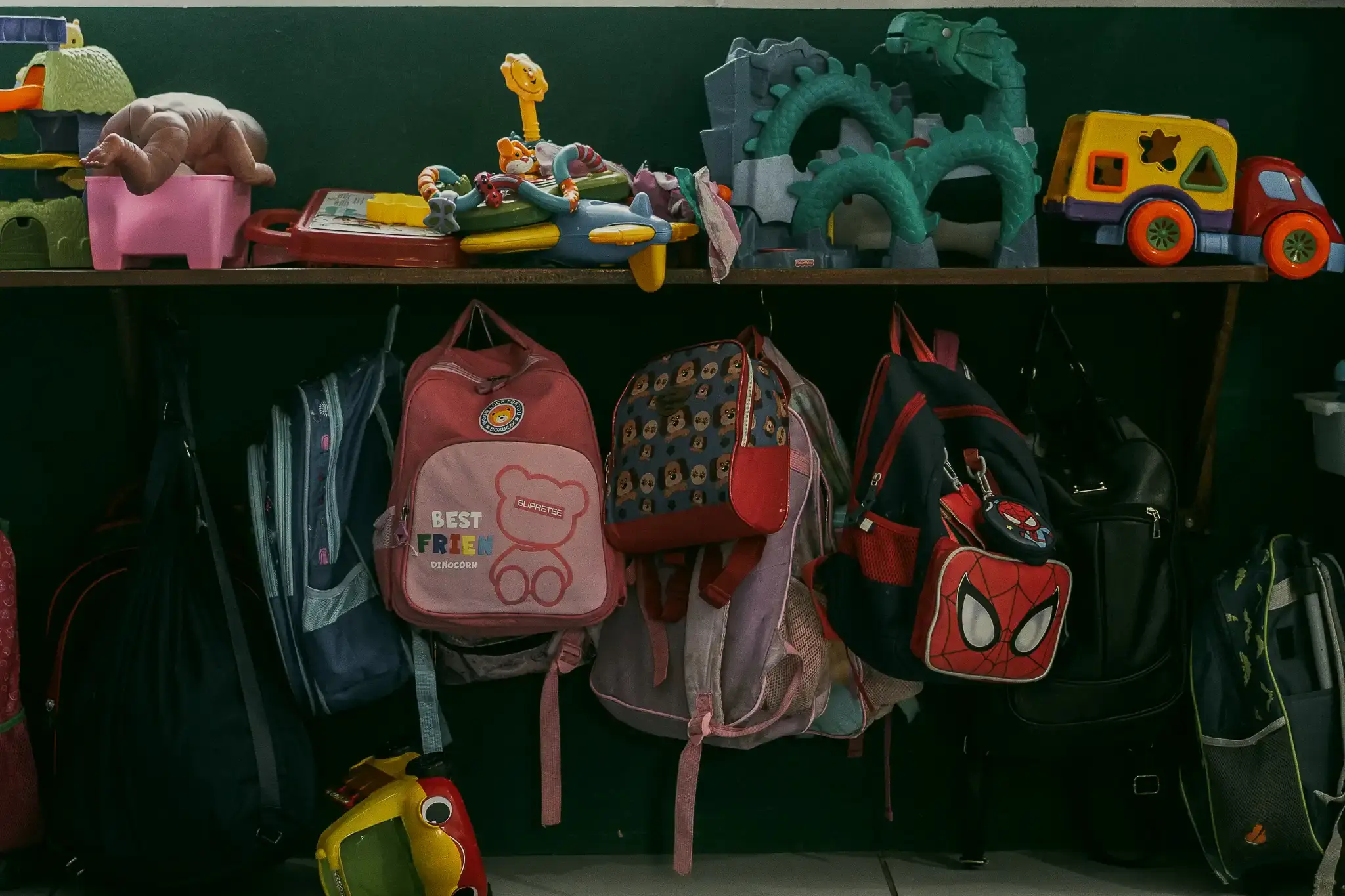 Mochilas e brinquedos pendurados na parede da escola Filhos do Céu