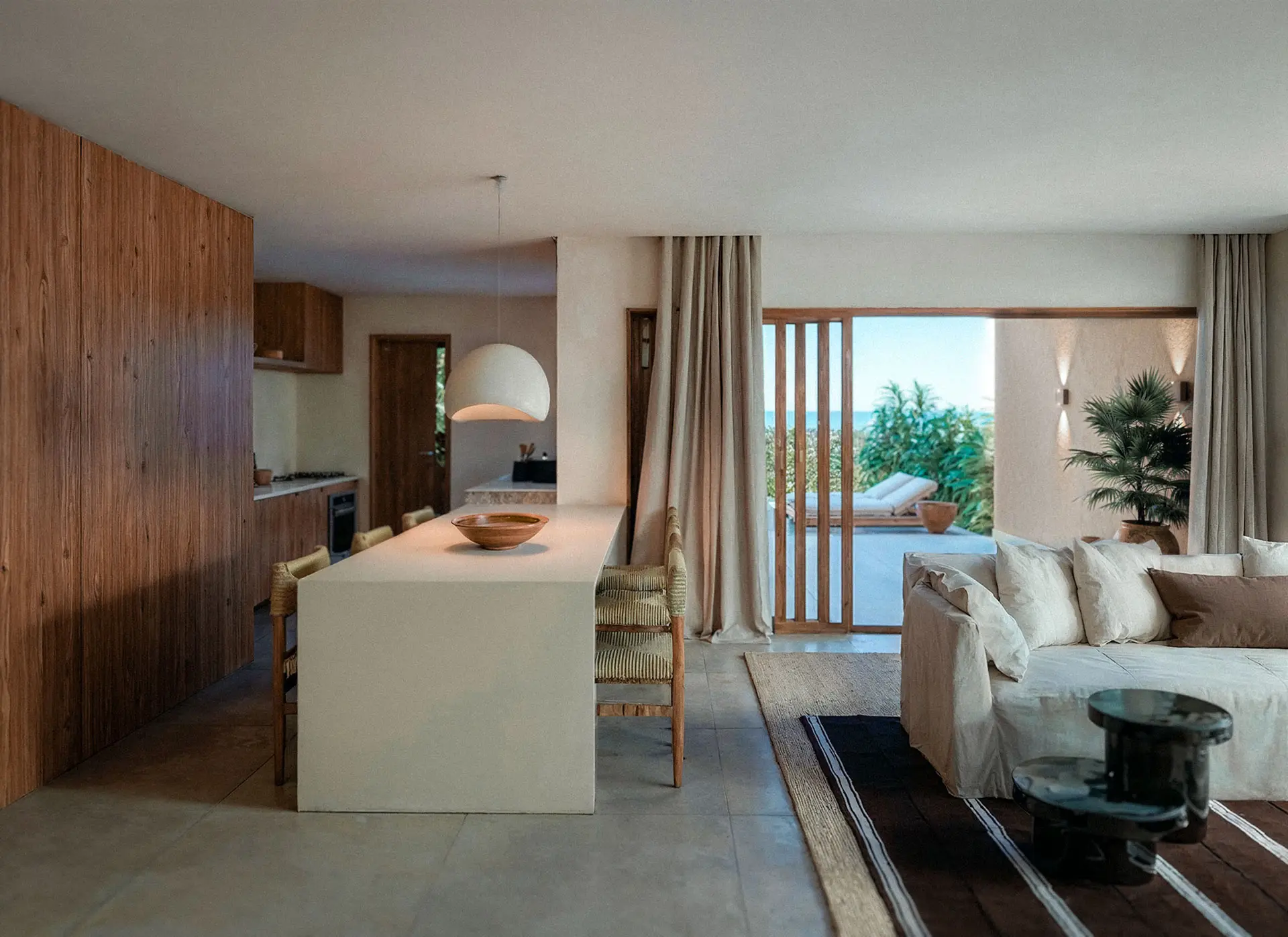 Vista living room with a kitchen island, light sofa and veranda behind