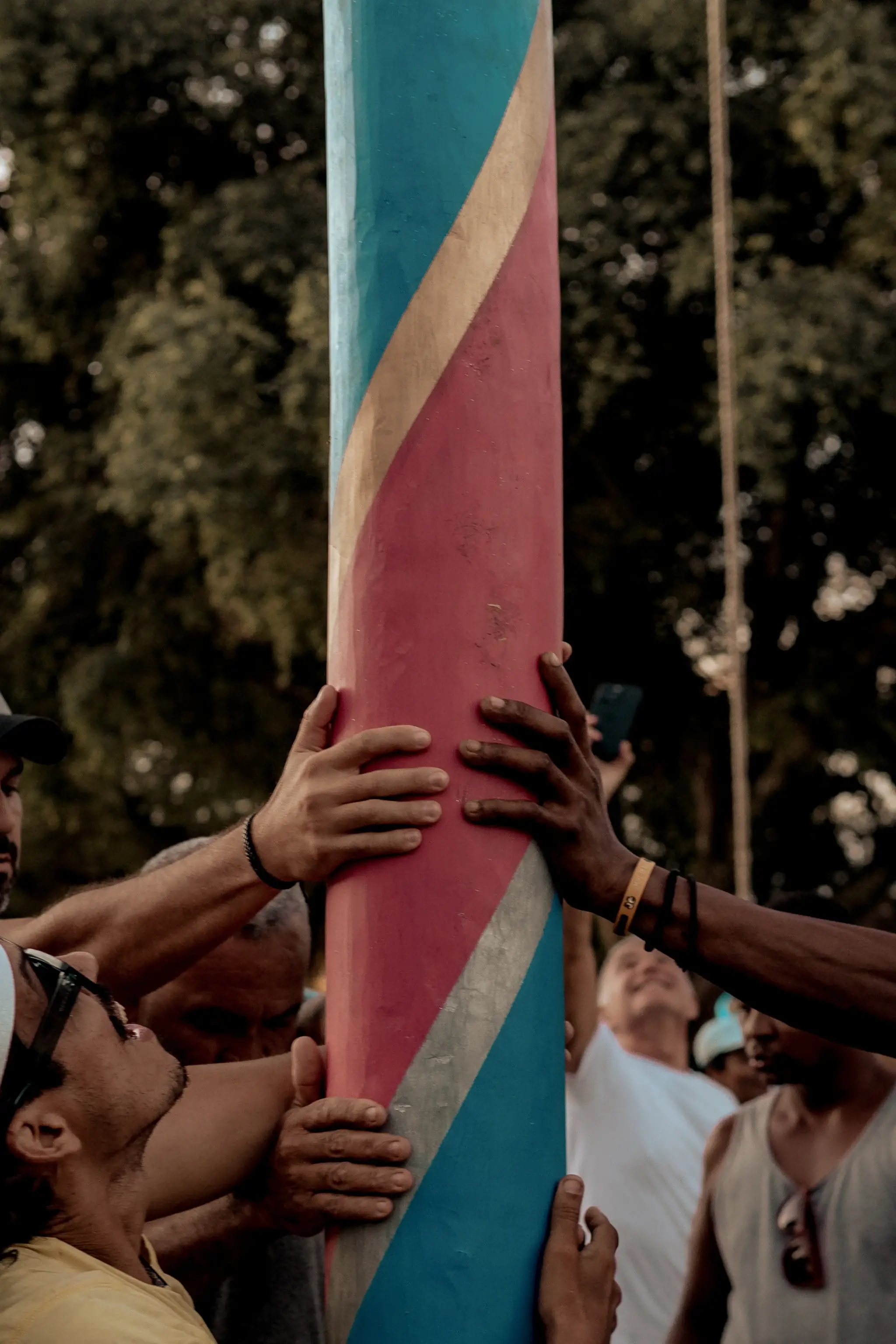 Mãos erguendo o mastro colorido da festa de São Brás em Trancoso