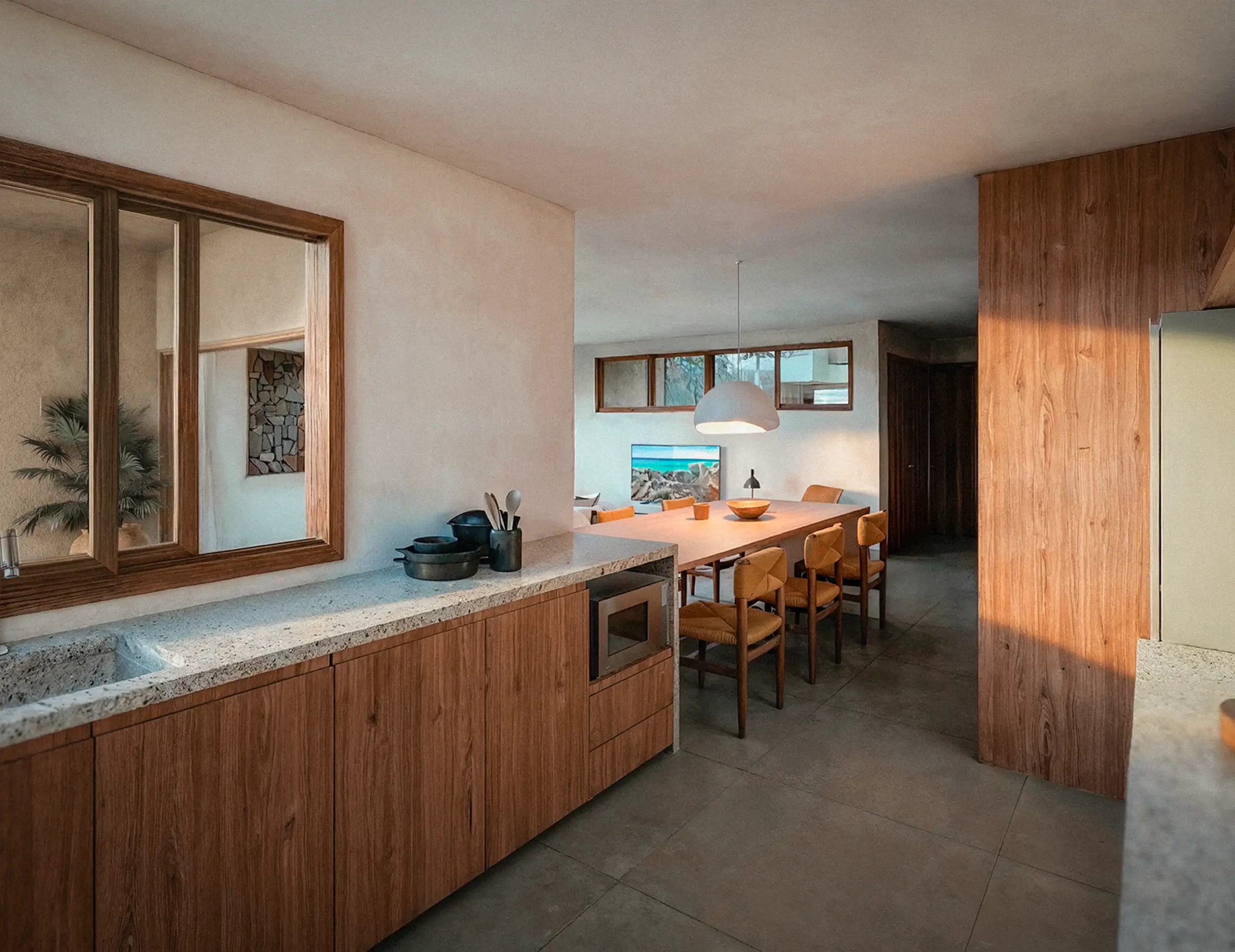 Kitchen with wooden cabinets, stone counters, an undermount sink and a microwave; wide windows above the sink, and a dining table behind, all in neutral tones.
