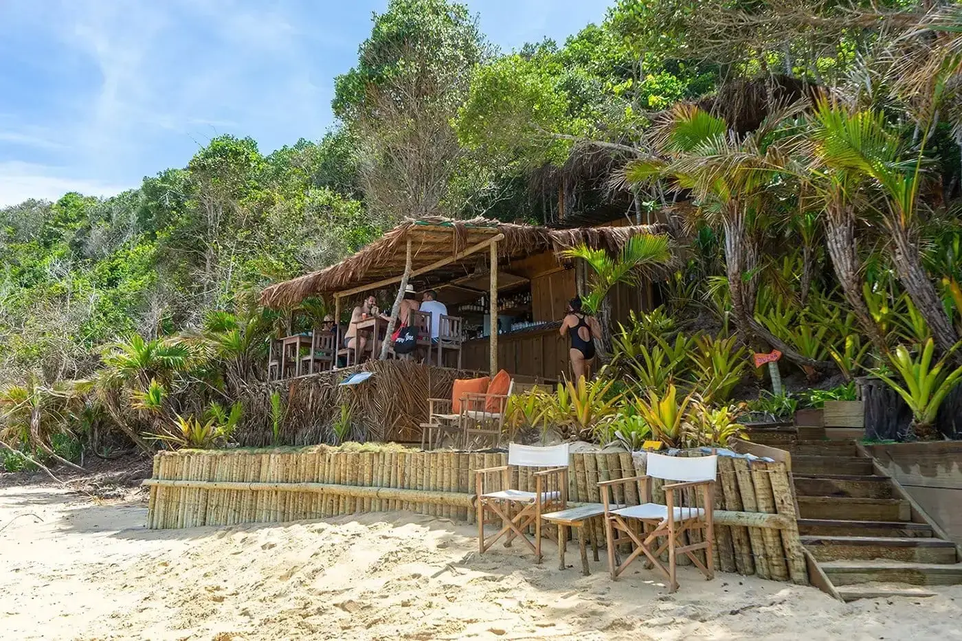 Beach bar with a thatched roof and canvas chairs on the sand in Caraíva