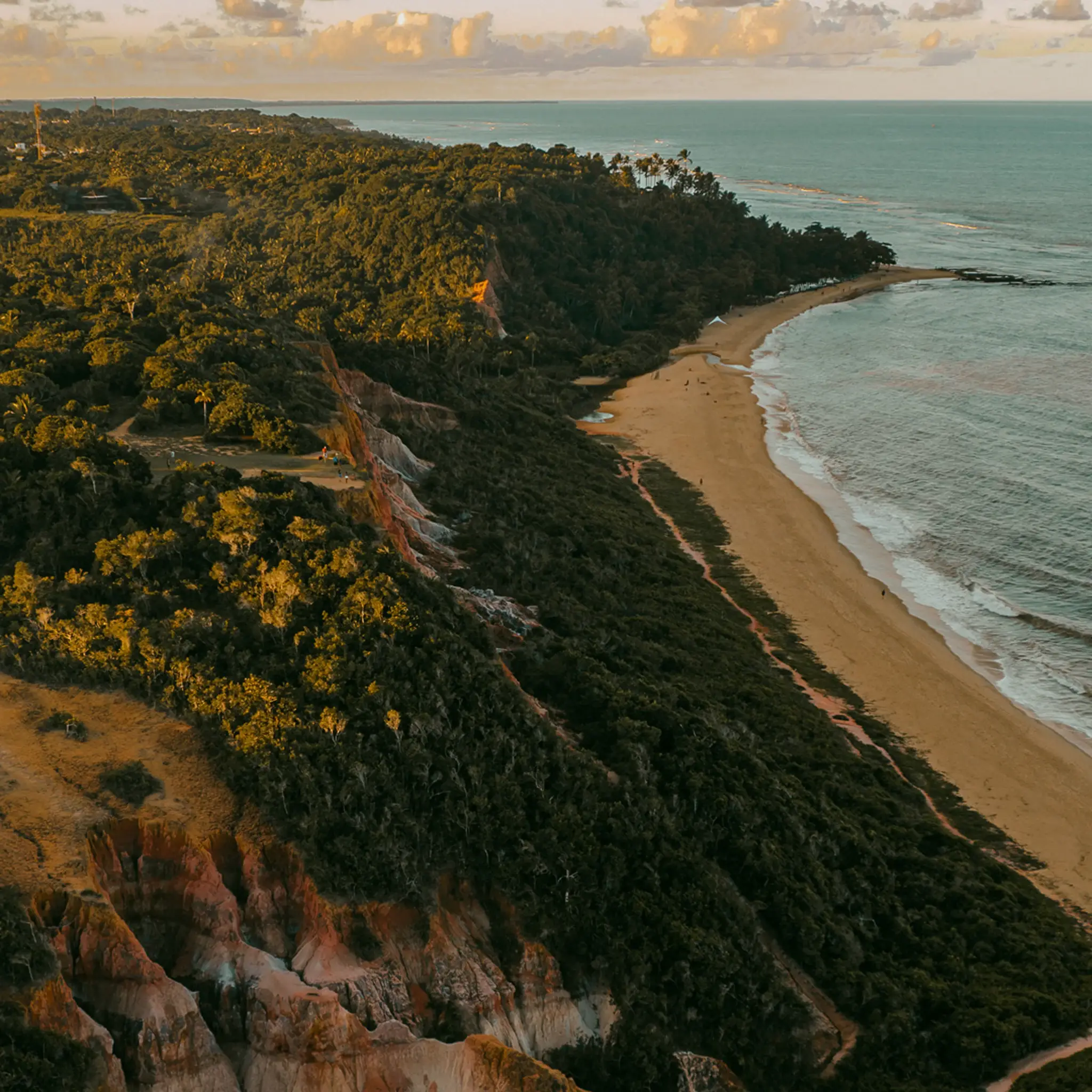 Vista aérea da costa de Arraial d'Ajuda: falésias, mata e praia ao entardecer