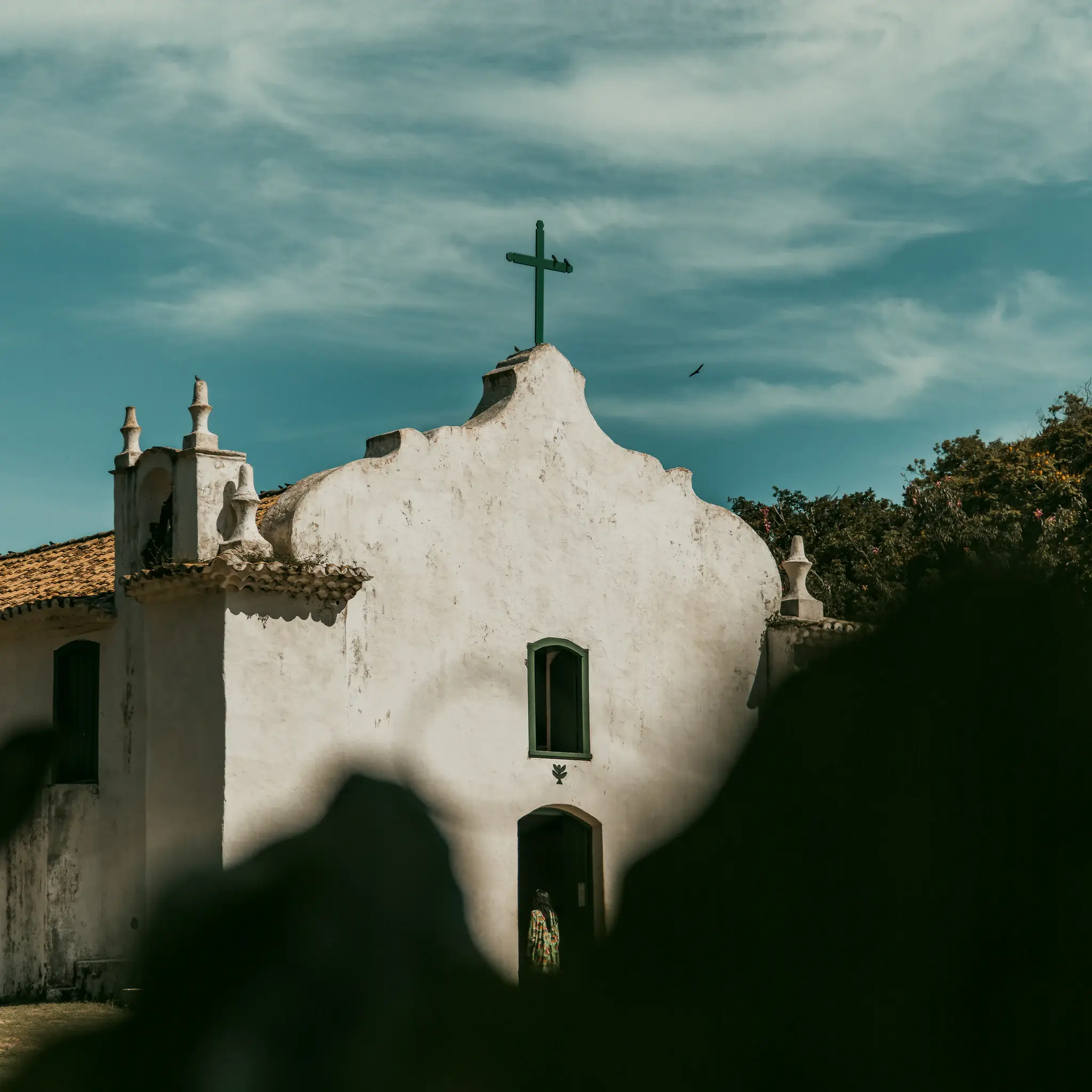 Fachada da igreja do Quadrado de Trancoso sob céu azul com nuvens