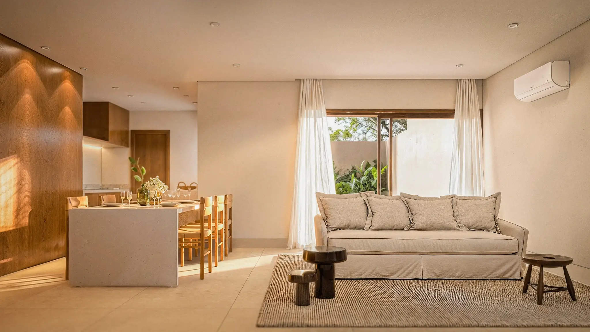 Open-plan living room and kitchen at VISTA, with a light sofa and curtains opening to the garden
