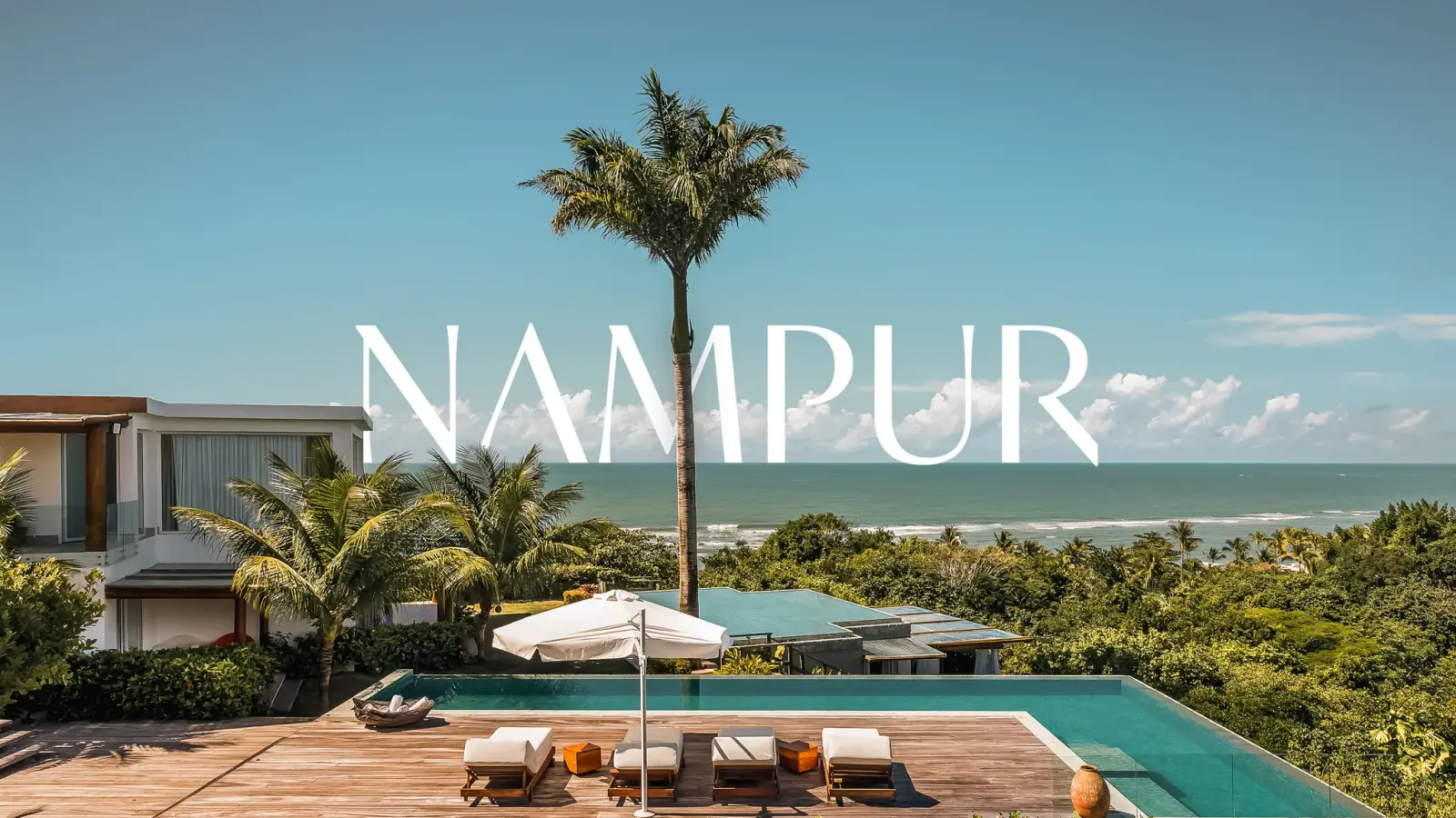 Deck com piscina e espreguiçadeiras entre coqueiros, mar ao fundo, com a marca Nampur sobre a imagem