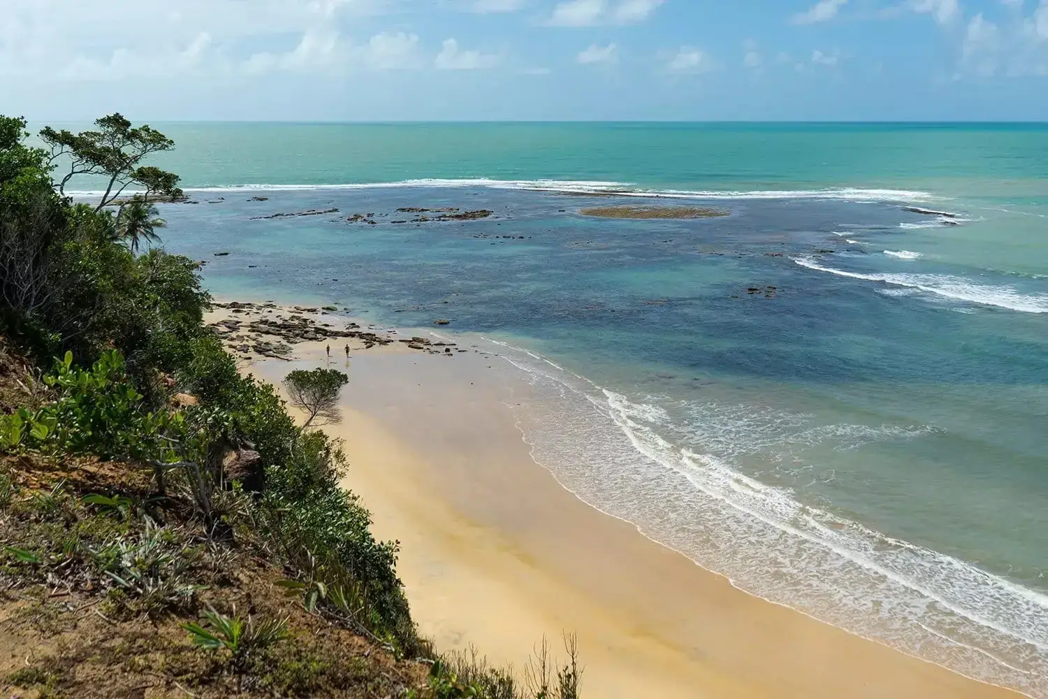 Satu beach seen from above: sand, greenish sea and forest on the slope
