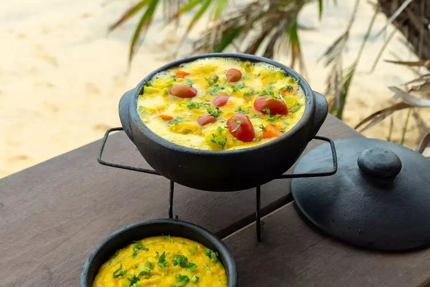 Moqueca stew in a clay pot on a trivet, with pirão on the side