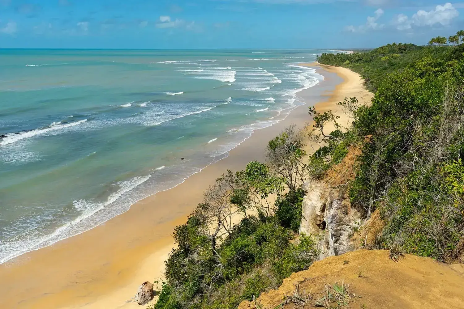 Long beach with cliffs behind seen from above, blue sea