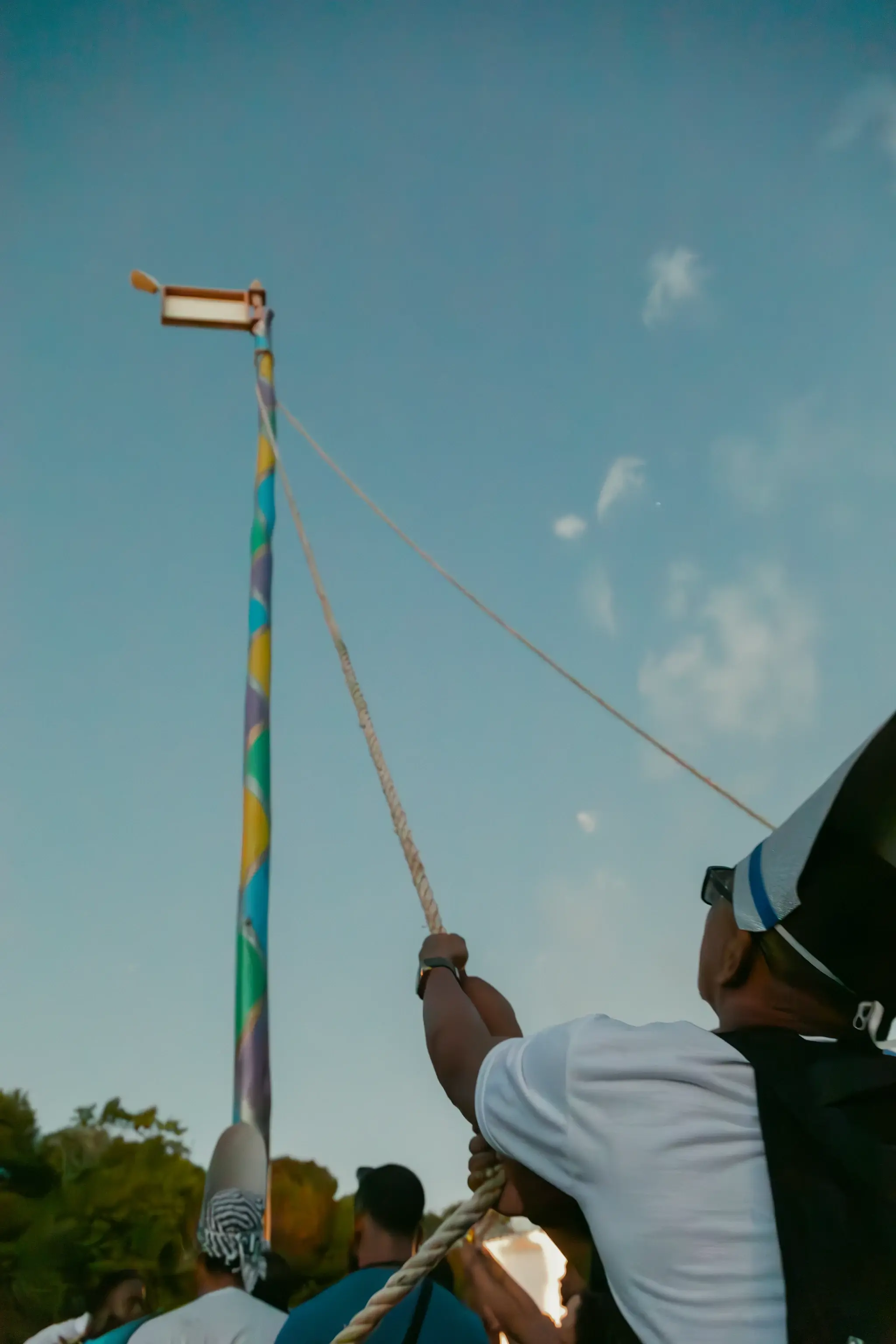 São Brás festival mast being hoisted with ropes against the sky